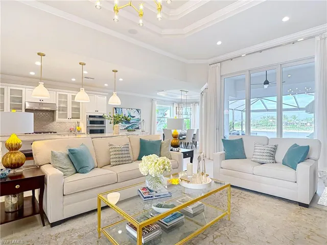Living area featuring recessed lighting, a raised ceiling, an inviting chandelier, and crown molding