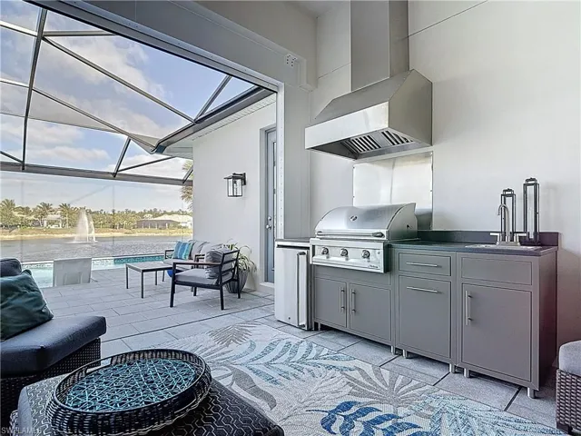 Outdoor screened lanai featuring picture frame screening overlooking large lake with lit fountains. Retractable electric awning,Storm Smart hurricane screen, summer kitchen and outdoor speakers.