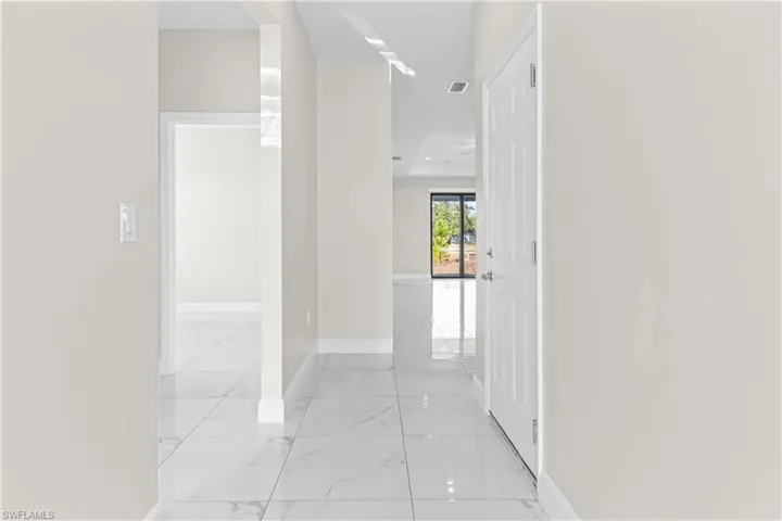 Hallway with baseboards and light marble finish floors
