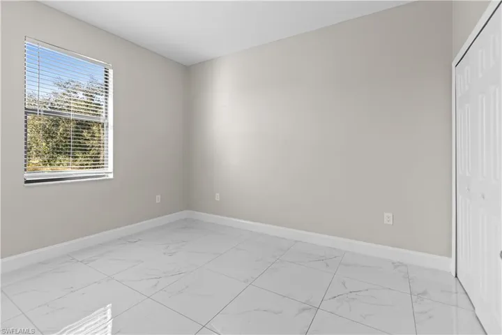Unfurnished bedroom featuring light marble finish flooring and a closet