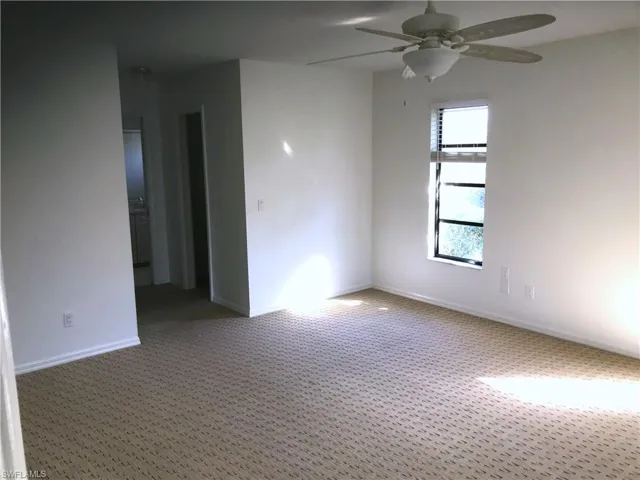 Empty room featuring a ceiling fan and carpet
