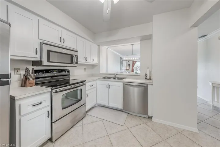 Kitchen featuring stainless steel appliances, white cabinets, sink, and ceiling fan