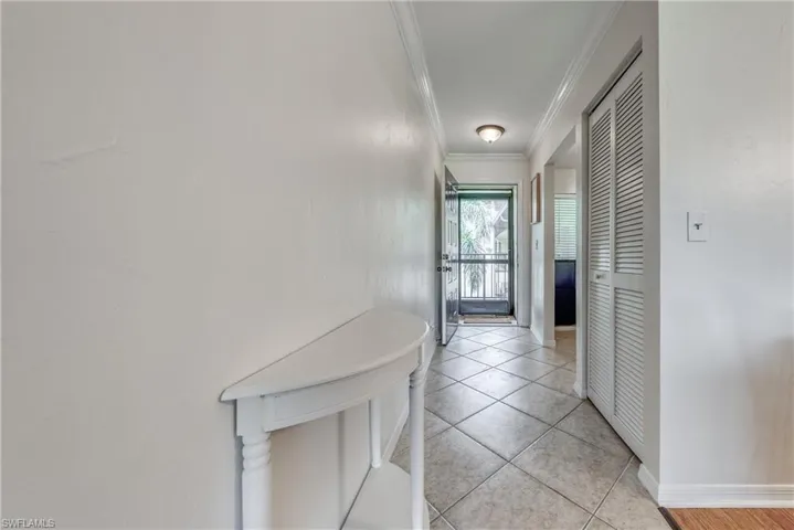 Hallway featuring light tile floors and crown molding