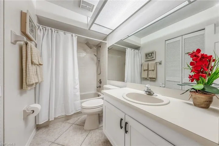 Full bathroom with tile floors, shower / tub combo with curtain, oversized vanity, and toilet