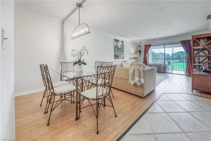 Tiled dining space featuring crown molding and an inviting chandelier