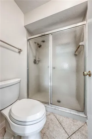 Bathroom featuring tile floors, a shower with shower door, and toilet