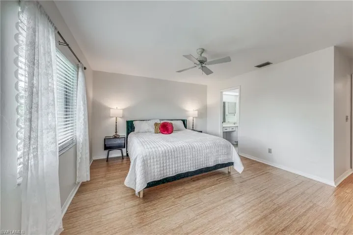 Bedroom featuring ceiling fan, ensuite bathroom, and light hardwood / wood-style flooring