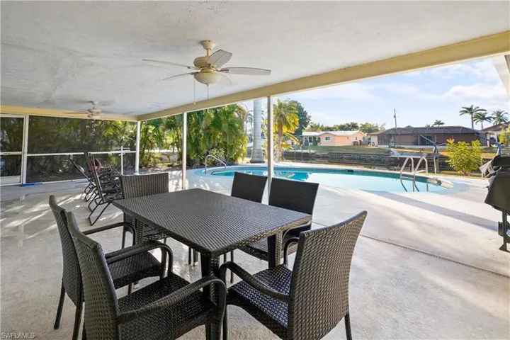 View of covered lanai over looking the pool, a ceiling fan, outdoor dining area faces south. Will be wonderful to enjoy your pool time!
