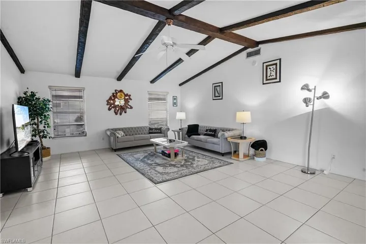 An expansive family room with high vaulted ceilings is open to the kitchen and opens to the covered lanai, pool, and Gulf access canal.