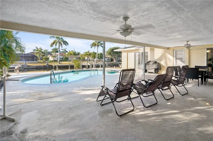 Solar heated swimming pool featuring a large covered patio area, outdoor dining space, and grilling area