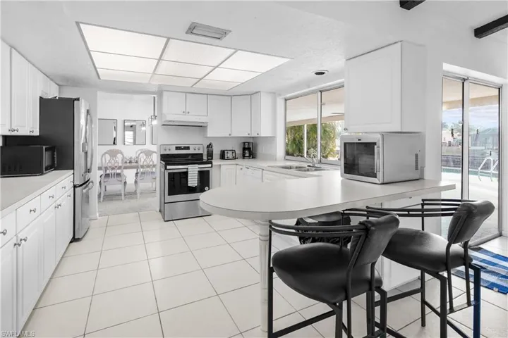Kitchen with stainless steel appliances, light countertops, white cabinets, a breakfast bar / peninsula. Great acces to the pool and covered lania!