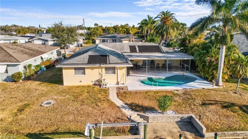 Back of house faces south with a large contrete pool deck area, solar panels to heat your pool, easy access to boat dock and lift.