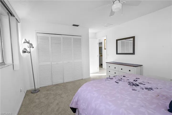 Bedroom featuring light carpet, ceiling fan, and a large reach-in closet.
