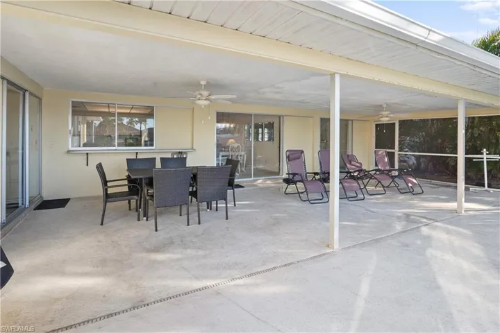 View of patio / terrace featuring two ceiling fans and outdoor dining space. The patio doors and kitchen window slide into the wall to give you full openings.