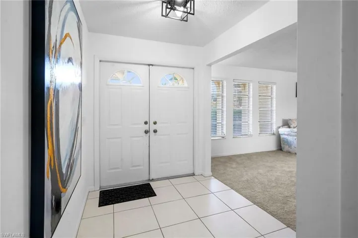 Foyer with double front door entry, opens to the L-shaped living room, has a garage enterance and leads to the family room kitchen area .