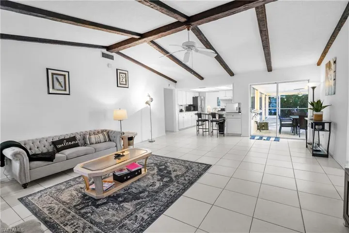 Family room with a ceiling fan, vaulted ceiling, and light colored large tile floors.