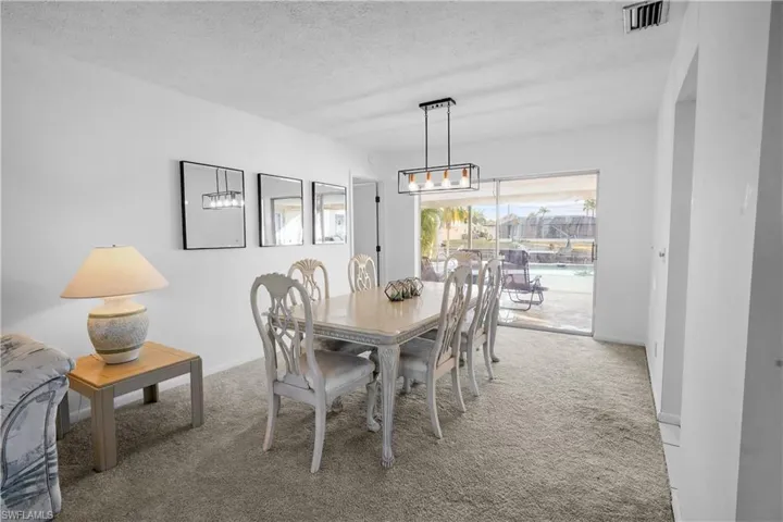 Dining area featuring light colored carpet opens to the pool.