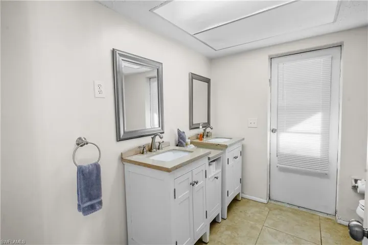 Full bath featuring two vanities, a combo tub bath. The guest bath opens to the pool.