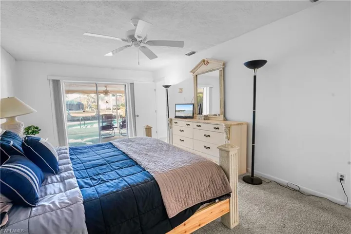 Carpeted bedroom overlooks the pool and water front, canal.