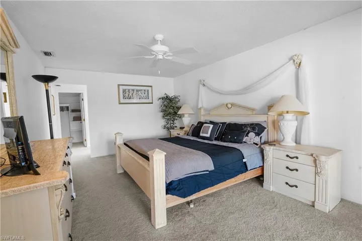 Bedroom with light colored carpet, ceiling fan, and a spacious closet