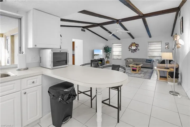 Kitchen featuring open floor plan, white cabinetry, a peninsula, light countertops, and stainless steel wine cooler.