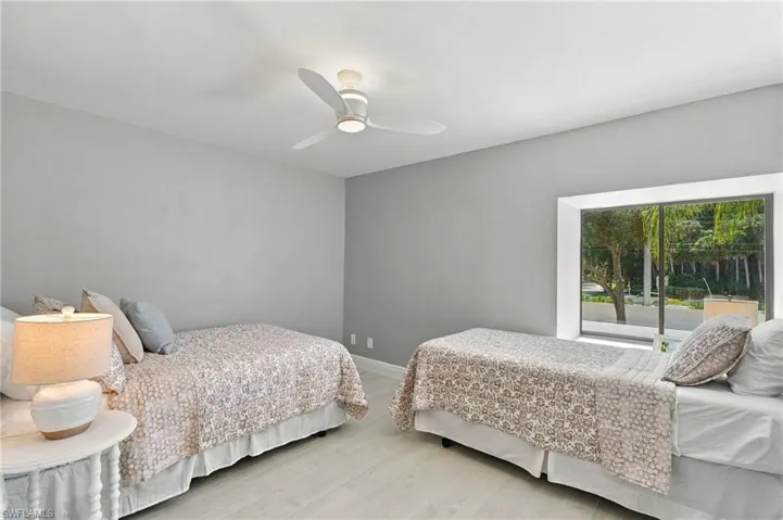 Neutral-toned interior featuring wood-finish flooring, a contemporary three-blade ceiling fan, and a large recessed window