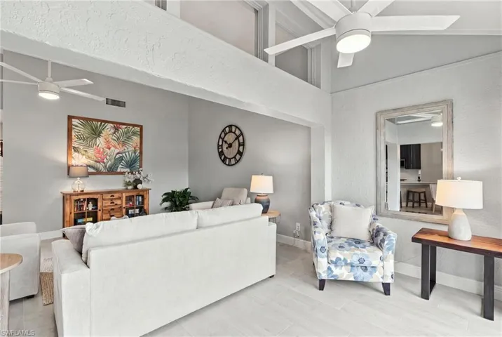 Vaulted ceilings with clerestory windows, neutral wall finishes, light-toned ceramic tile flooring, and dual modern ceiling fans with integrated lighting