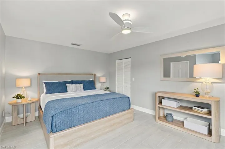 Neutral-toned interior space featuring light-colored tile flooring, a modern three-blade ceiling fan with integrated lighting, and louvered closet doors