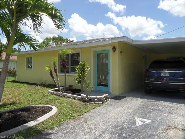 View of front of house featuring driveway, stucco siding, and a carport