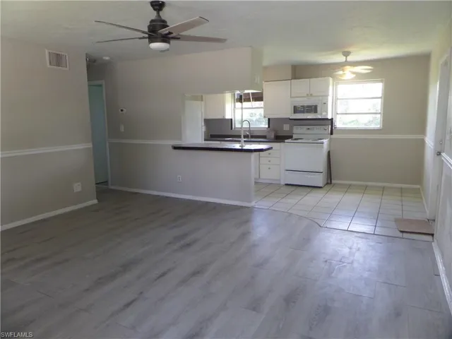 Kitchen featuring white appliances, ceiling fan, white cabinetry, and plenty of natural light
