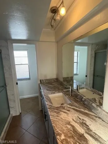 Bathroom with vanity, walk in shower, and tile patterned flooring