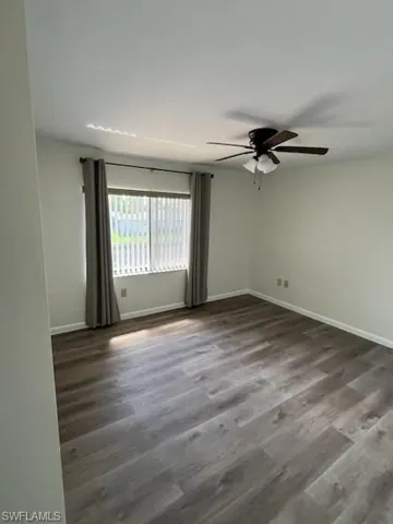 Empty room featuring ceiling fan and dark hardwood / wood-style floors