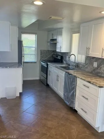 Kitchen featuring sink, dishwashing machine, white cabinets, and stainless steel range with electric stovetop