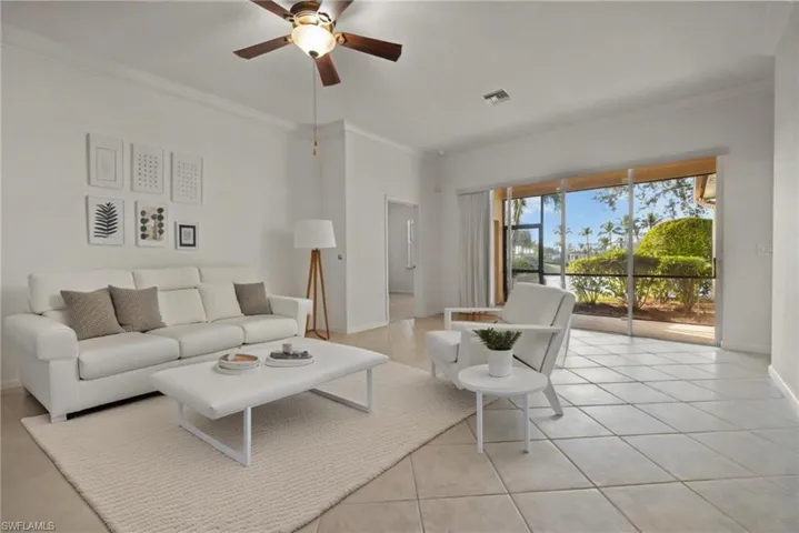 Living area featuring light tile patterned floors, baseboards, visible vents, and ornamental molding