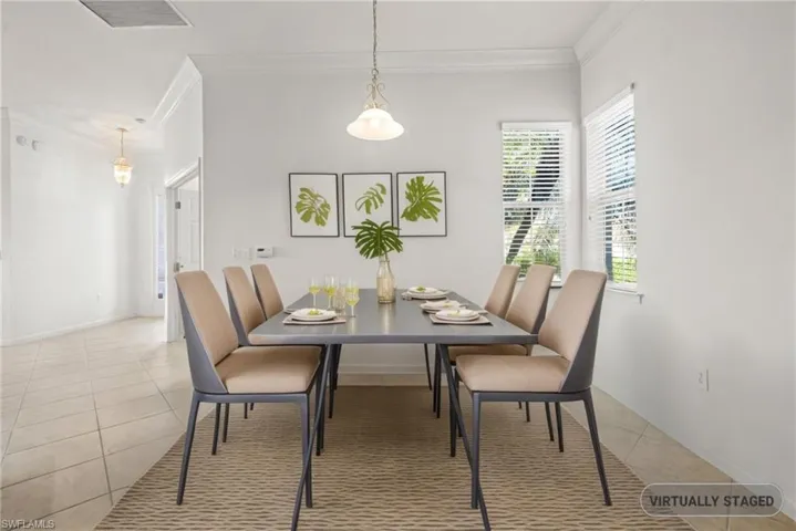 Dining room featuring light tile patterned floors, visible vents, baseboards, and ornamental molding