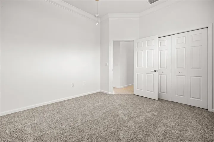 Unfurnished bedroom featuring crown molding, carpet, and a closet