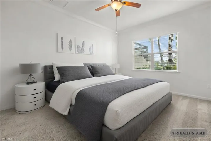 Carpeted bedroom with ceiling fan, baseboards, and ornamental molding
