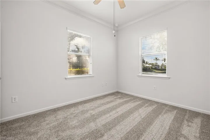 Carpeted spare room featuring crown molding and ceiling fan