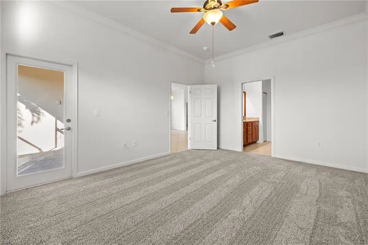 Carpeted empty room featuring crown molding and ceiling fan