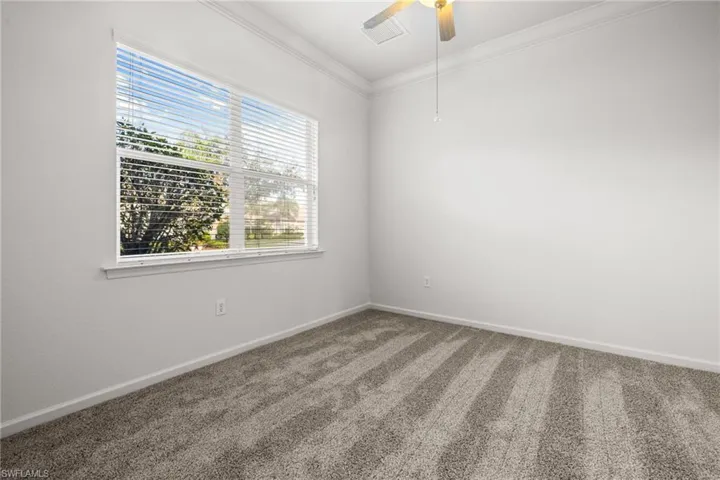 Carpeted spare room featuring crown molding and ceiling fan