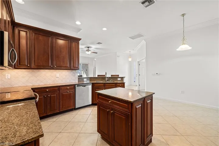 Kitchen with pendant lighting, a kitchen island, granite countertops, and appliances with stainless steel finishes