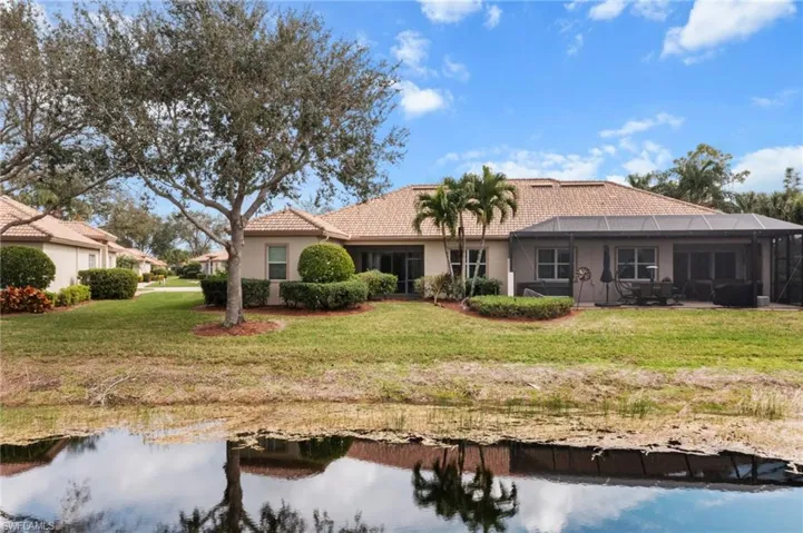 Rear view of house with a lanai and a lawn