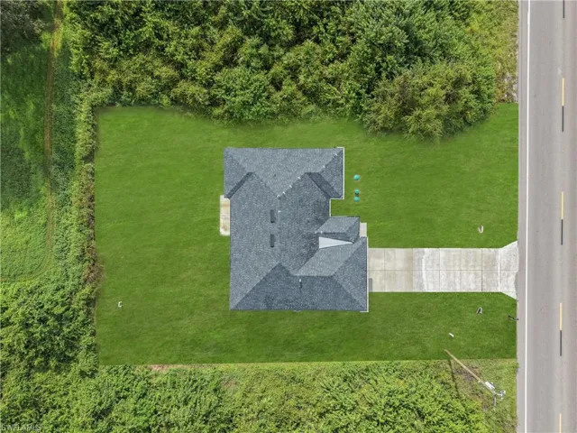 Expansive lot with a single-family residence, mature perimeter landscaping, and a paved driveway directly accessible from a public road