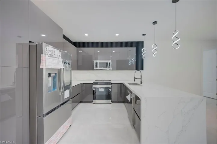 Kitchen with a peninsula, modern cabinets, stainless steel appliances, and light stone countertops
