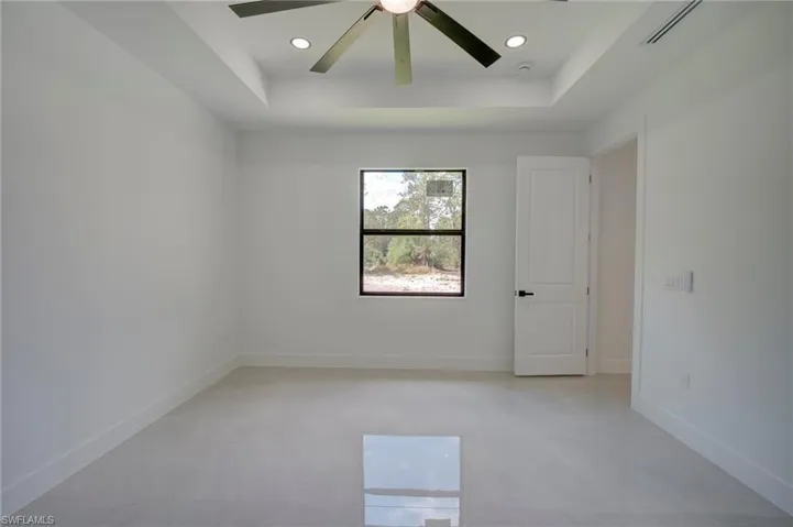 Empty room featuring a tray ceiling, a ceiling fan, and recessed lighting
