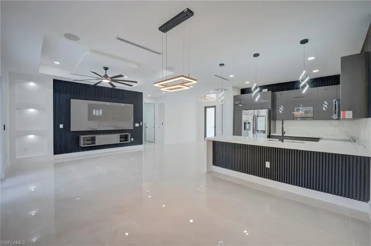 Kitchen featuring a peninsula, light stone counters, modern cabinets, and stainless steel fridge