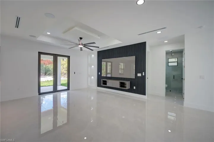 Unfurnished living room featuring a ceiling fan, a raised ceiling, and recessed lighting