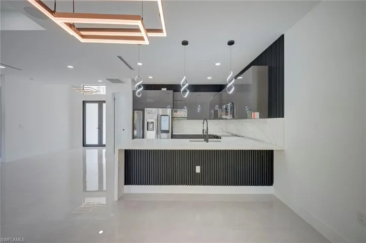 Kitchen featuring modern cabinets, a peninsula, light stone countertops, stainless steel appliances, and a breakfast bar area