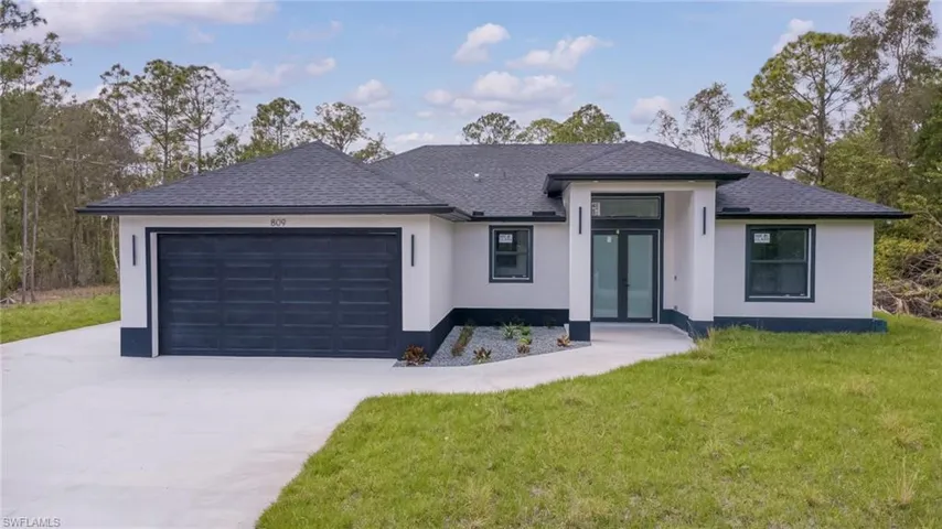 View of front of home featuring a garage, a front yard, stucco siding, driveway, and roof with shingles