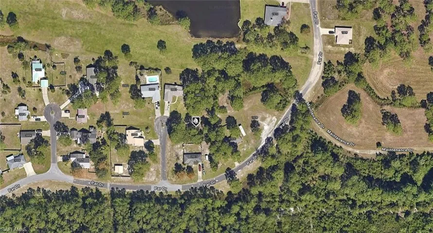 Aerial perspective featuring a spacious lot with mature trees, established landscaping, and direct frontage on a paved thoroughfare